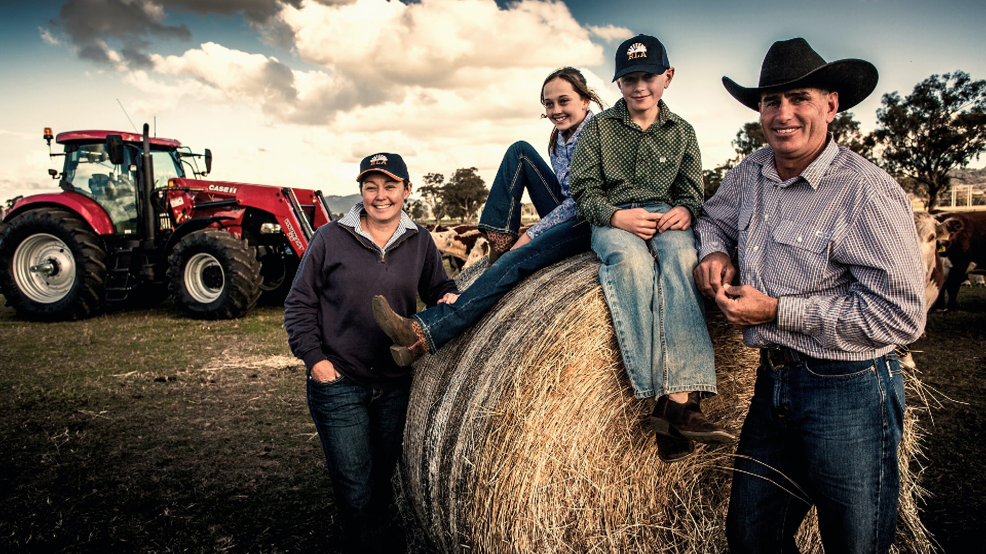 Happy family on a farm posing in front of a CASE IH tractor